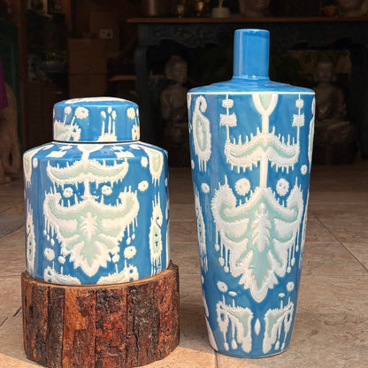 A short, cylindrical handpainted ceramic ginger jar featuring a vibrant blue and white ikat pattern with a matching lid, displayed in a modern luxury living room setting.