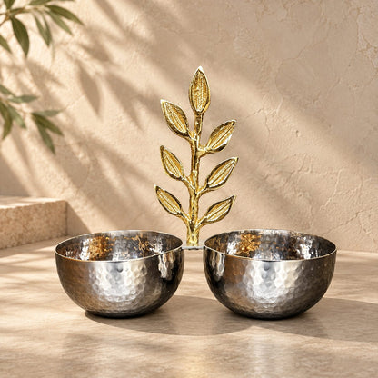 Inara luxury silver hammered stainless steel double bowl with an ornate brass golden leaf motif handle set against a warm neutral studio backdrop.