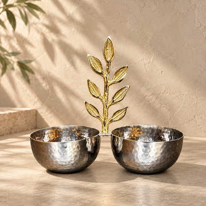 Inara luxury silver hammered stainless steel double bowl with an ornate brass golden leaf motif handle set against a warm neutral studio backdrop.