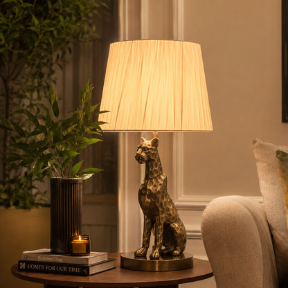 Elegant antique brass leopard table lamp creating warm ambient lighting on a wooden side table beside a sofa in a luxury living room.