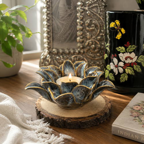 Lotus bloom ceramic tealight holder with candle placed on a wooden table in an elegant home décor setting with warm natural lighting.