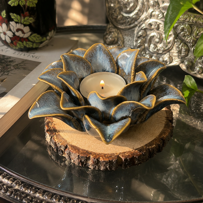 Blue ceramic lotus tealight holder styled on a rustic wooden coaster with elegant home décor accents in a cozy sunlit setting.