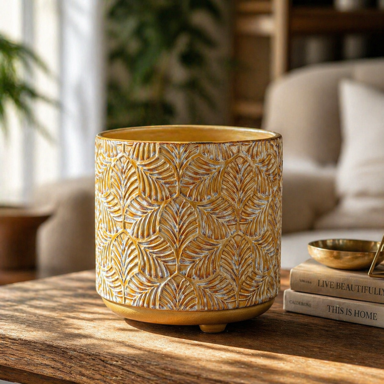 Luxury hand-painted ceramic pot with high-relief textures and a metallic gold base, styled in a warm, naturally lit living room.