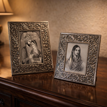 Luxury heritage home interior with antique silver handcrafted photo frames featuring intricate floral embossing, styled on a dark wooden console table with warm ambient lighting and a royal Indian décor aesthetic.