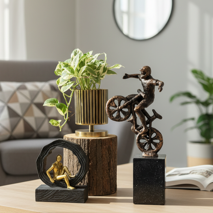 A luxury bronze biker figurine styled on a wooden coffee table next to a gold-ribbed planter and a contemporary circular sculpture in a bright, modern living room.