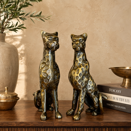 Luxury bronze leopard pair sculptures styled on a premium wooden tabletop against a warm beige Venetian plaster wall, creating an elegant luxury home décor setting by Inara Home Decor.