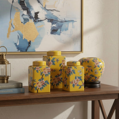 A collection of yellow floral ceramic jars and a round vase styled on a wooden console table beneath abstract wall art.