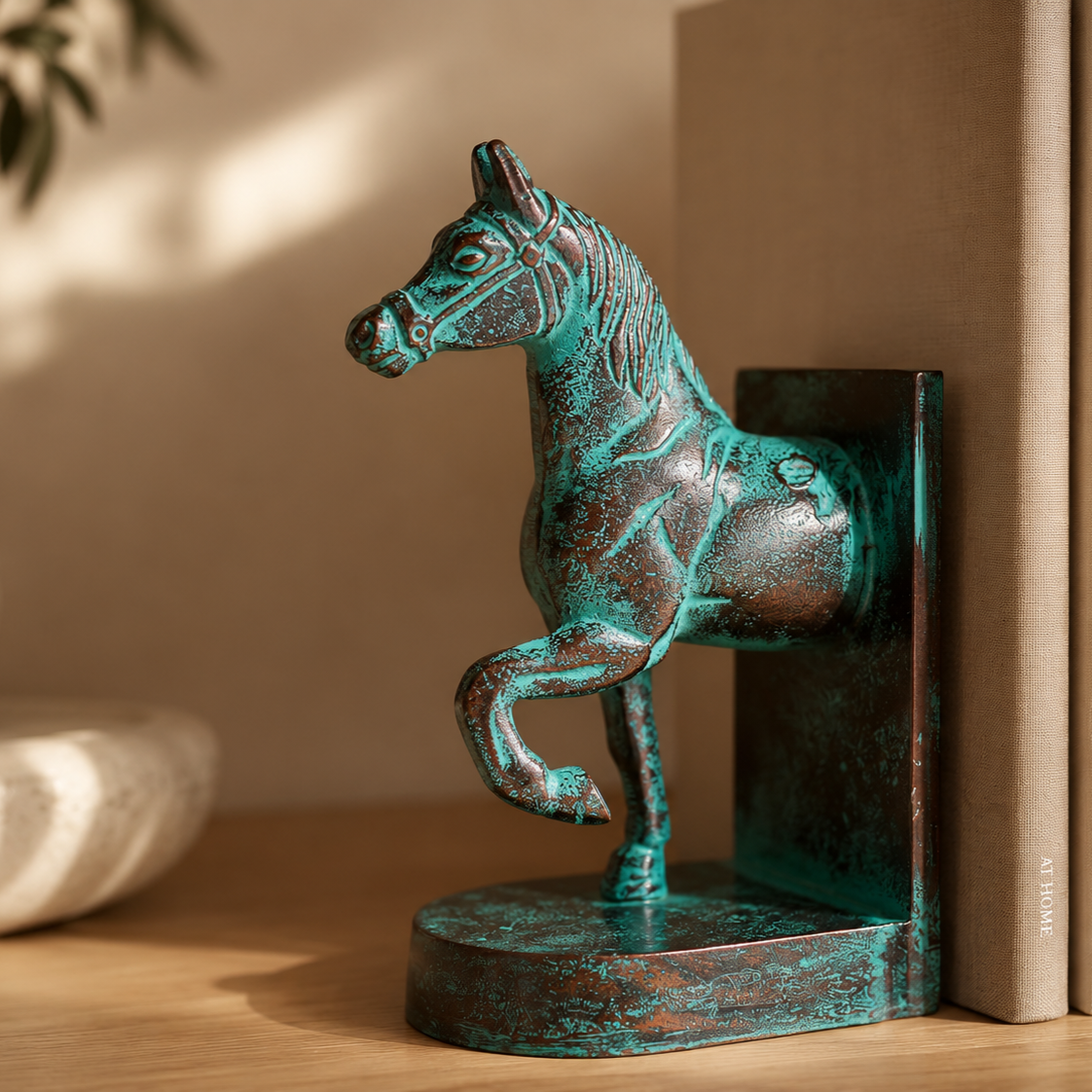 Luxury verdigris horse bookend sculpture in antique patina finish displayed on a wooden shelf beside books, handcrafted decorative bookend for elegant modern home décor by Inara Home Decor.
