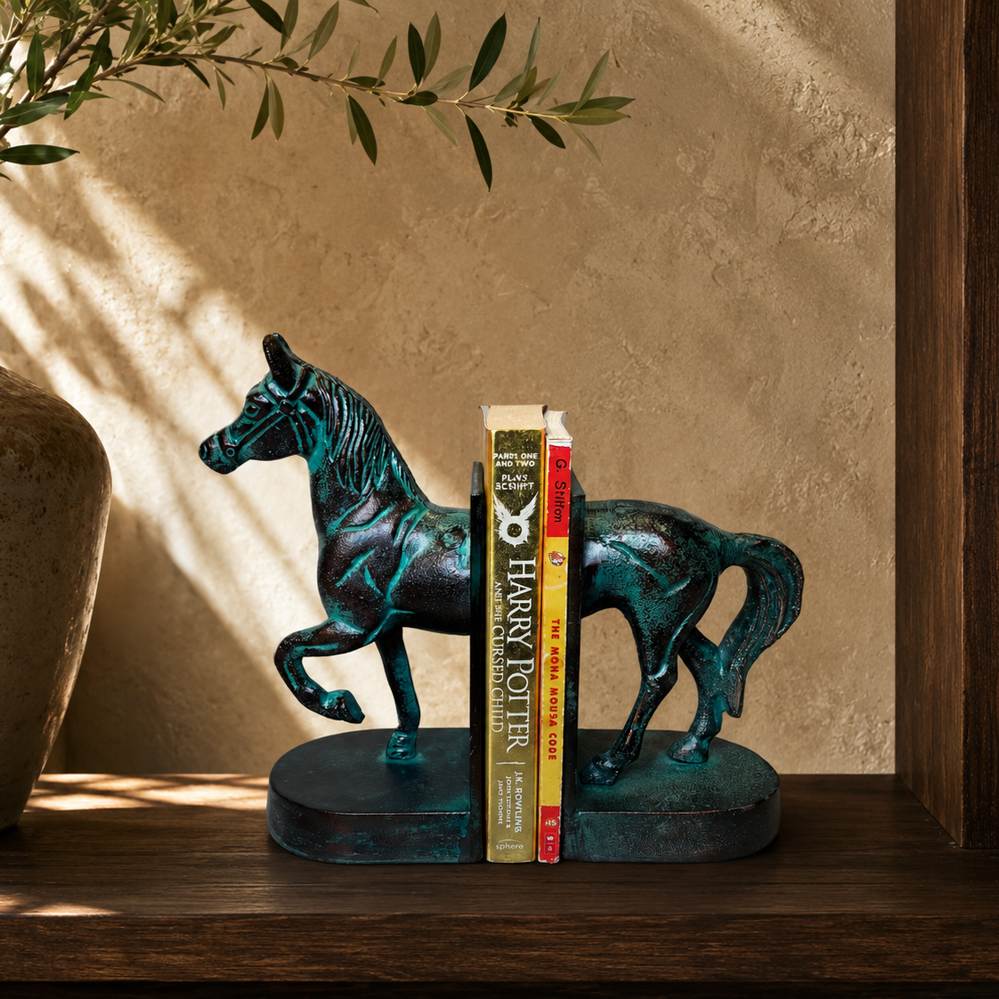 Luxury verdigris horse bookends displayed on a dark walnut bookshelf with books, ceramic vase, and olive branches, handcrafted metal bookends for elegant home library and office décor by Inara Home Decor.