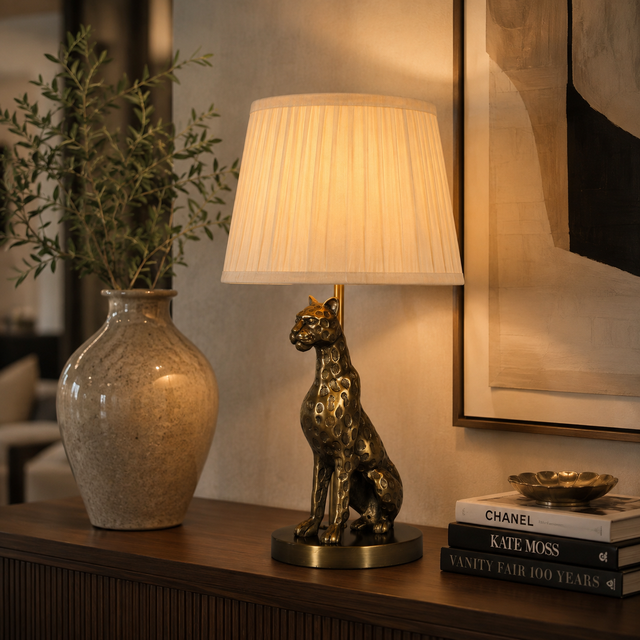 Luxury antique brass leopard table lamp styled on a wooden console table with decorative vase and books in a modern living room.