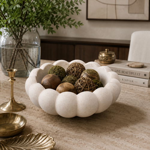 White scalloped ceramic decorative bowl styled on a luxury console table with decorative spheres in a modern contemporary home interior.