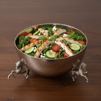 A premium silver-toned metal bowl with horse-shaped legs, filled with a fresh Mediterranean chicken salad and placed on a dark wooden tabletop.