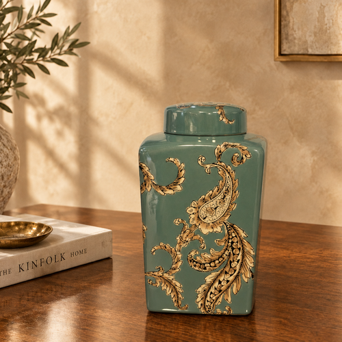Luxury teal ceramic decorative jar with ornate gold paisley detailing displayed on a dark walnut console table in an elegant modern living room setting by Inara Home Decor.