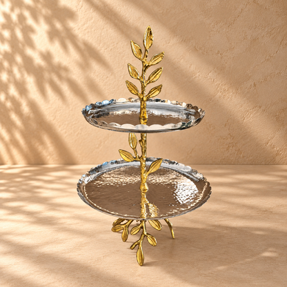 Luxury two tier leaf serving stand with hammered silver trays and gold leaf stem on a premium beige studio backdrop by Inara Home Decor.