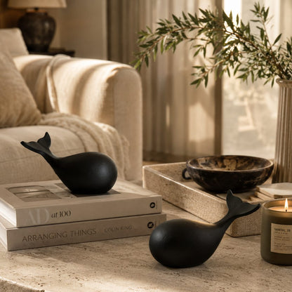 Minimalist black whale sculpture set styled on a luxury coffee table with books and candle in a modern living room.