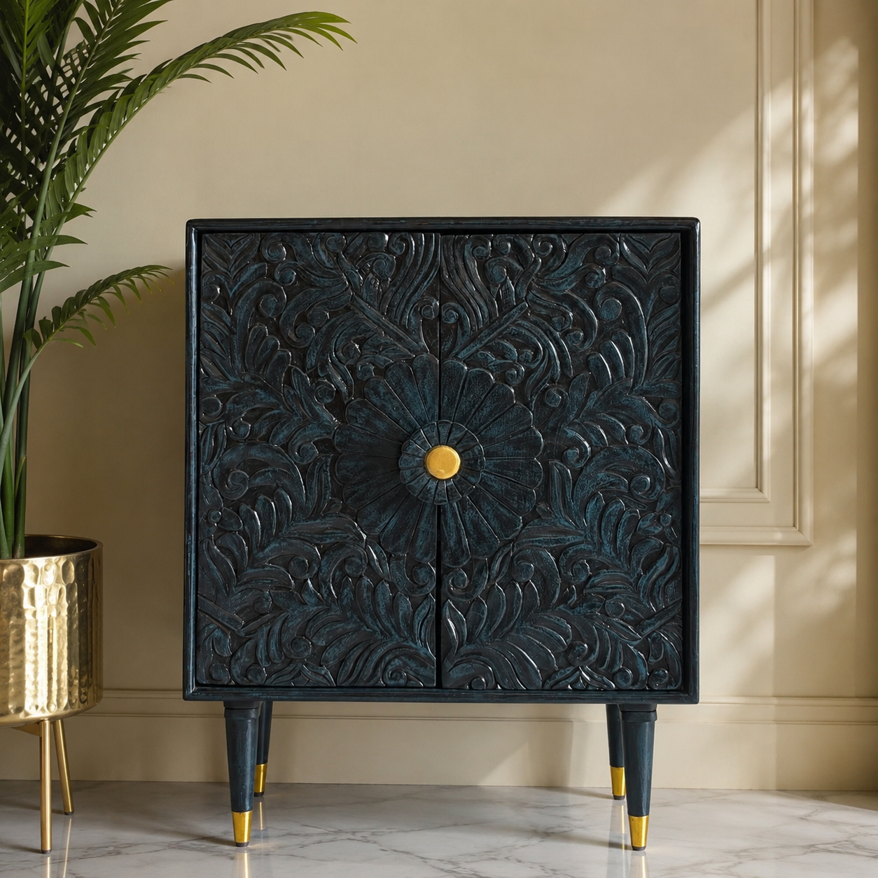 Hand-carved dark blue wooden accent cabinet with intricate floral carvings and gold knob, styled in a luxurious modern living room with natural daylight.