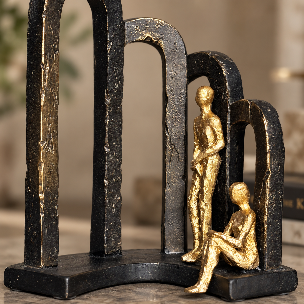Close-up of Modern Togetherness resin sculpture showcasing textured black arches and metallic gold figurines with premium craftsmanship.