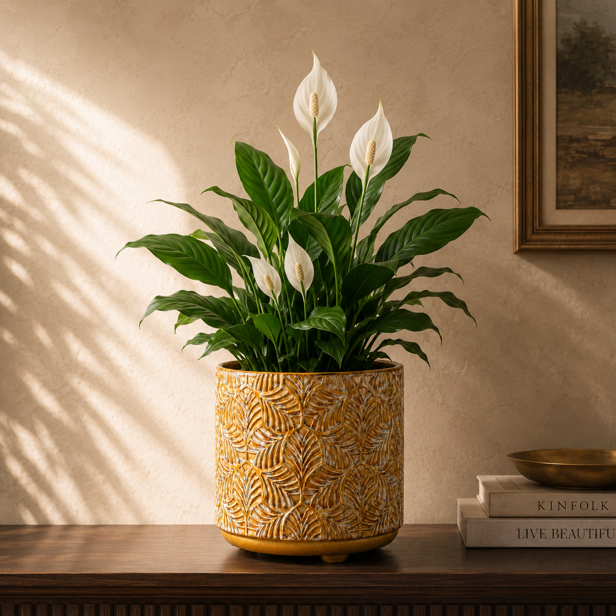 Mustard yellow embossed ceramic planter with leaf texture holding a Peace Lily, styled on a wooden console in a luxury living room.