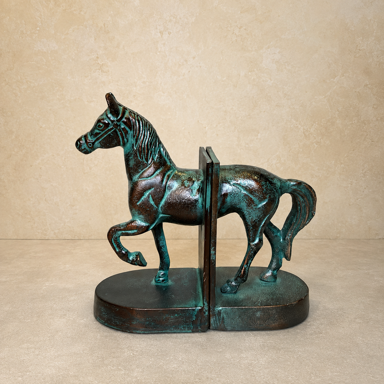 Patina horse bookends with a verdigris antique finish, handcrafted metal horse sculpture bookends on a luxury beige studio background, premium home décor by Inara Home Decor.