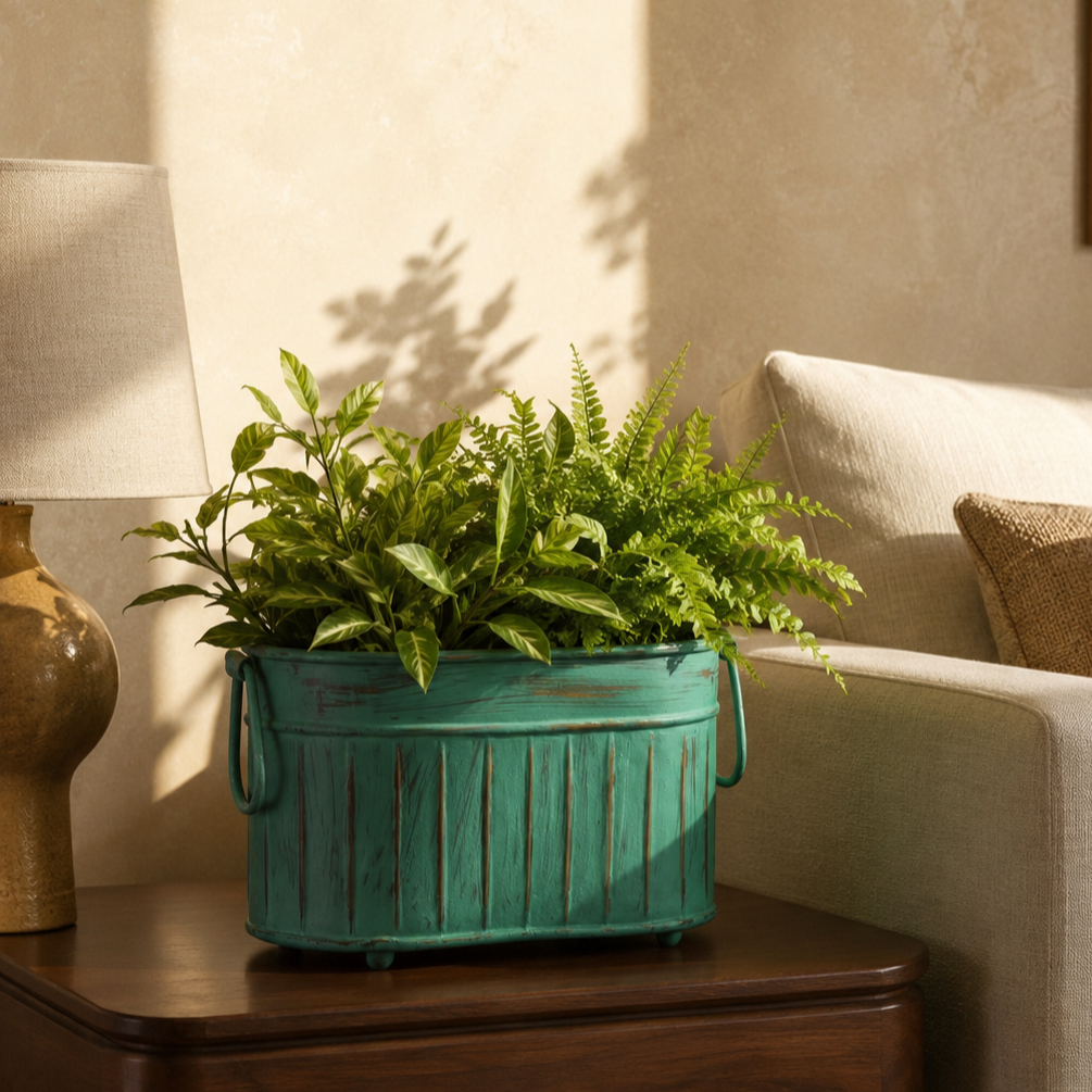 Vintage patina ribbed metal planter filled with lush green indoor plants styled on a walnut wood side table beside a cream sofa in a luxury living room.