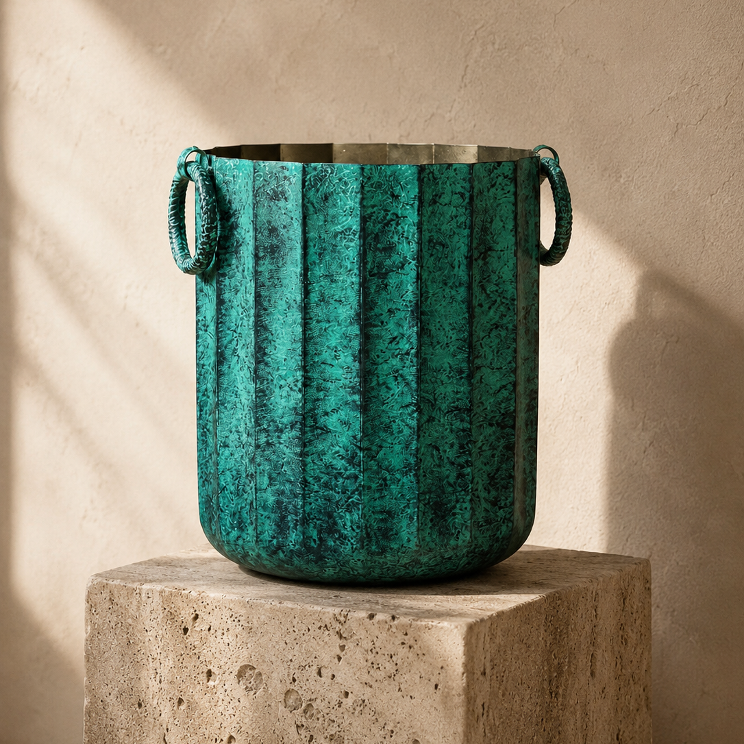 Vintage green metal planter with decorative ring handles displayed on a travertine pedestal featuring an antique textured finish for luxury home décor.