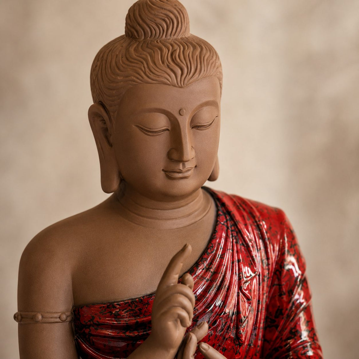 Close-up of handcrafted Buddha statue highlighting serene facial details, premium resin craftsmanship and glossy red robe finish.