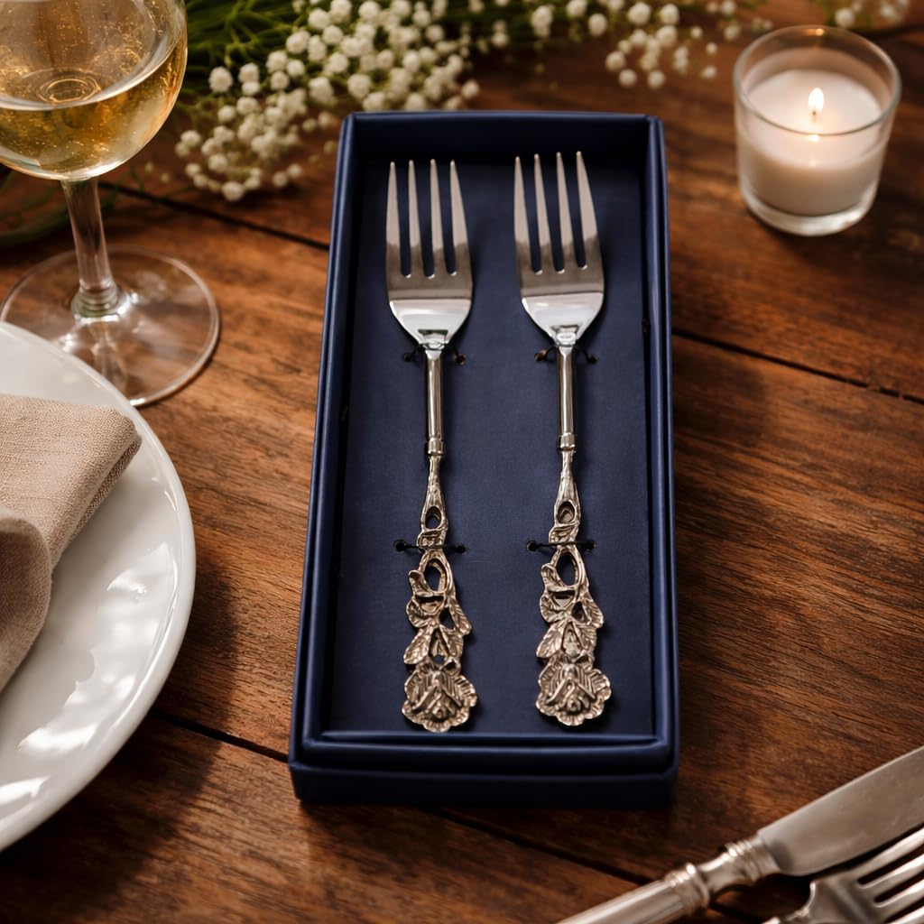 A pair of premium silver-plated forks secured in a navy blue luxury gift box, presented on a wooden table with candlelight and white flowers.