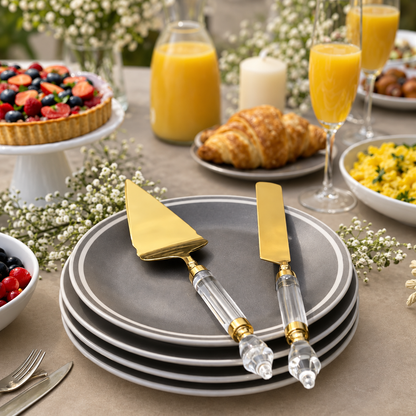 Premium Gold Cake Server & Knife Set with Clear Acrylic Handles displayed on elegant grey dinner plates in a luxury brunch table setting with fruit tart, croissants and orange juice.