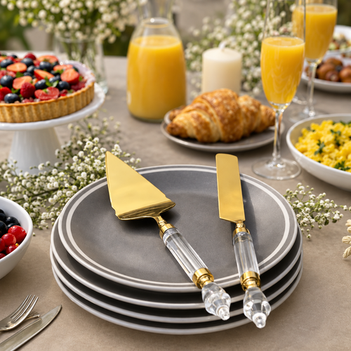 Premium Gold Cake Server & Knife Set with Clear Acrylic Handles displayed on elegant grey dinner plates in a luxury brunch table setting with fruit tart, croissants and orange juice.