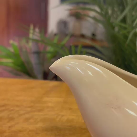 Video showing the detailed craftsmanship of a vintage-inspired white ceramic gravy boat with twisted handle styling, displayed as elegant tabletop home decor.