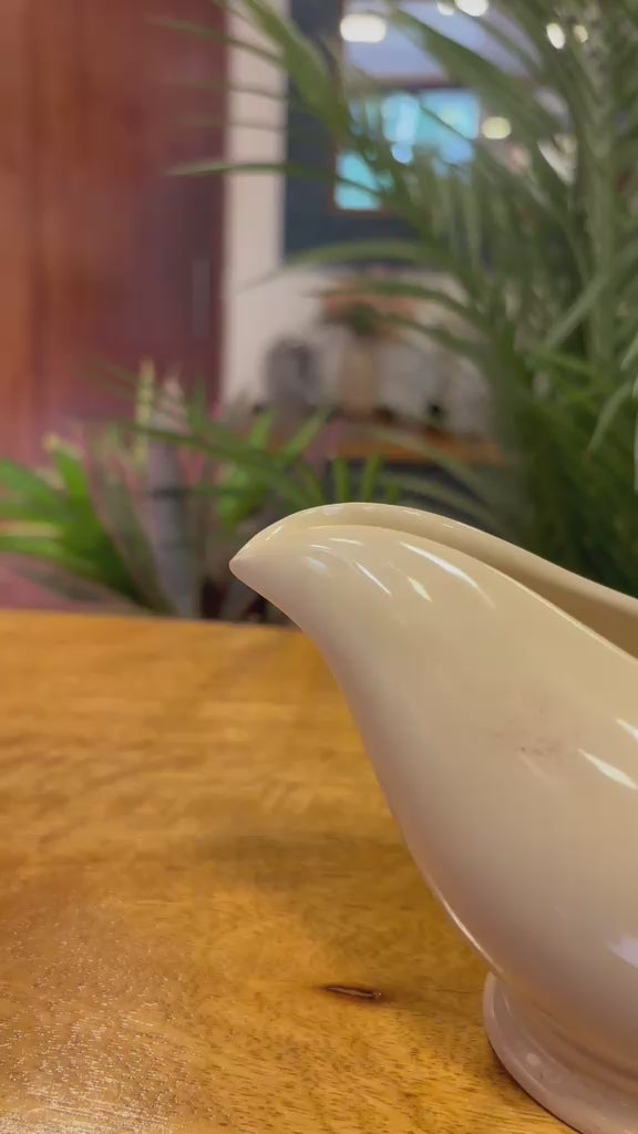 Video showing the detailed craftsmanship of a vintage-inspired white ceramic gravy boat with twisted handle styling, displayed as elegant tabletop home decor.
