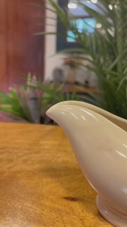 Video showing the detailed craftsmanship of a vintage-inspired white ceramic gravy boat with twisted handle styling, displayed as elegant tabletop home decor.