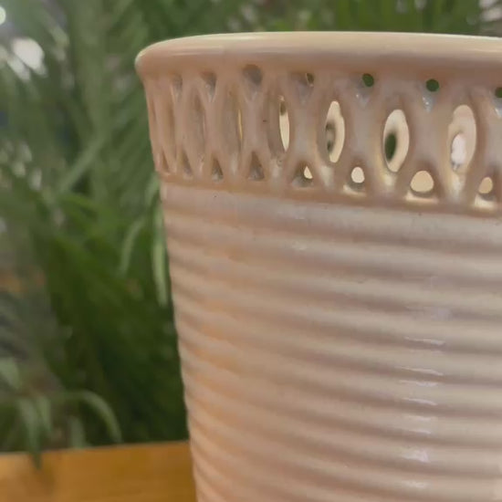Close-up video showcasing the detailing of an off-white ceramic ribbed planter with intricate cutwork rim design and elegant handcrafted finish.