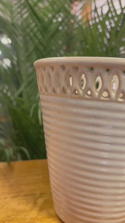 Close-up video showcasing the detailing of an off-white ceramic ribbed planter with intricate cutwork rim design and elegant handcrafted finish.