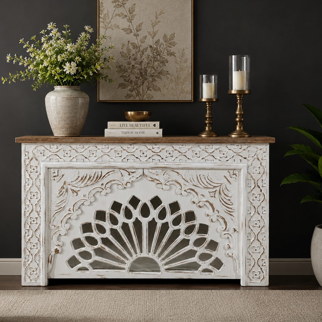 Handcrafted distressed white wooden console table with intricate floral carvings and a natural wood top, styled in a luxury living room against a dark wall.