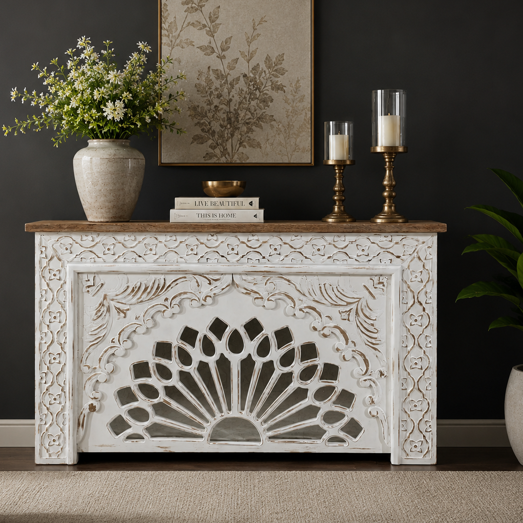 Handcrafted distressed white wooden console table with intricate floral carvings and a natural wood top, styled in a luxury living room against a dark wall.