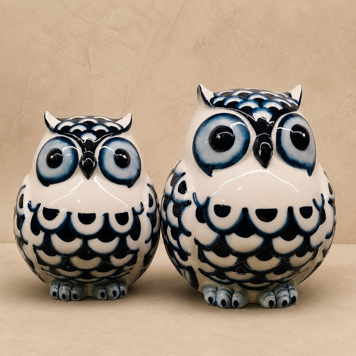 Blue and white hand-painted ceramic owl figurines set with a glossy finish, displayed on a premium beige studio backdrop, luxury decorative home accent for living room, console table, or shelf.