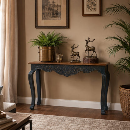 Hand-carved blue wooden console table with intricate floral detailing styled in a luxury living room featuring elegant décor, indoor plants, and a warm neutral interior.