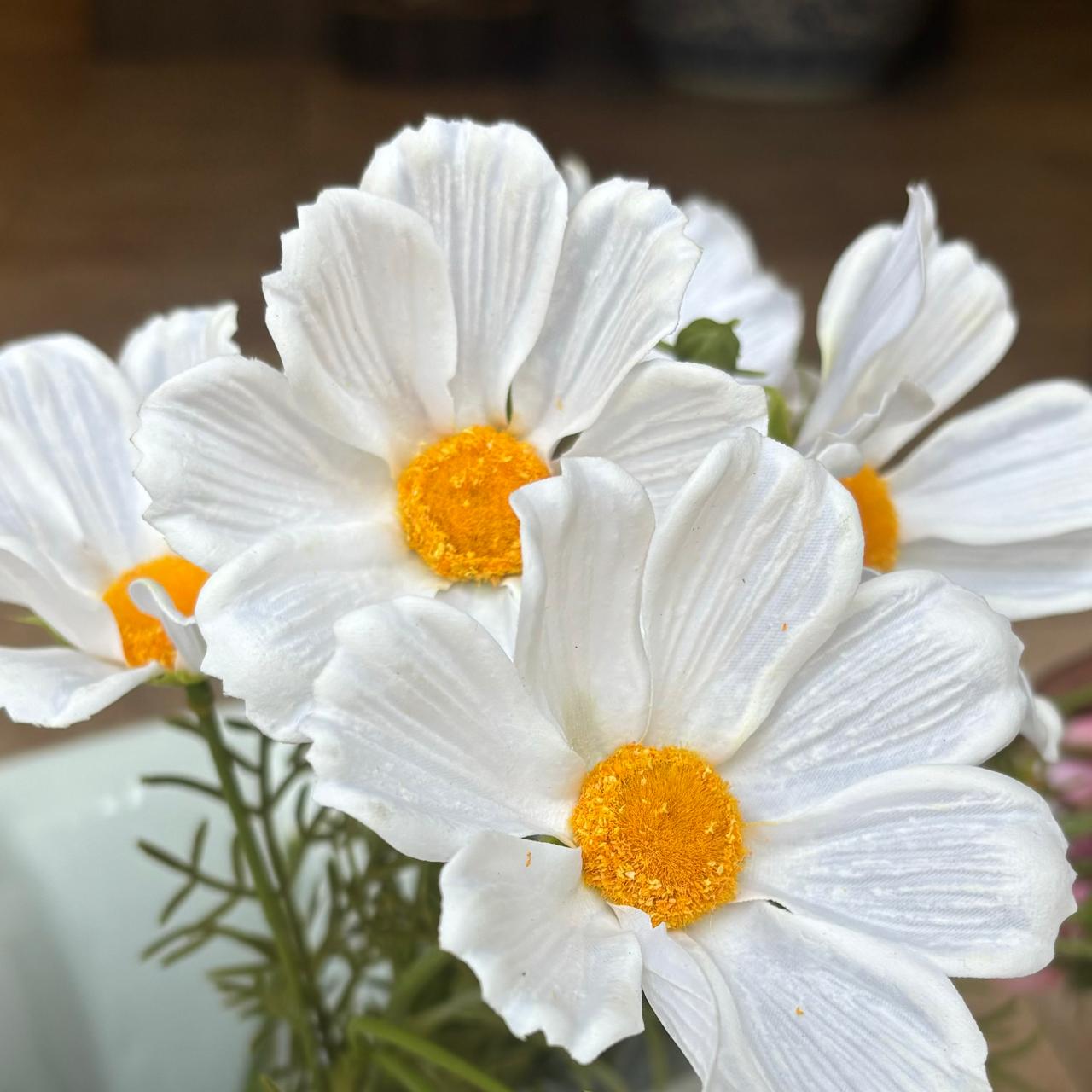 Close-up of real-touch artificial white cosmos flowers with vibrant yellow centres and lifelike petals.