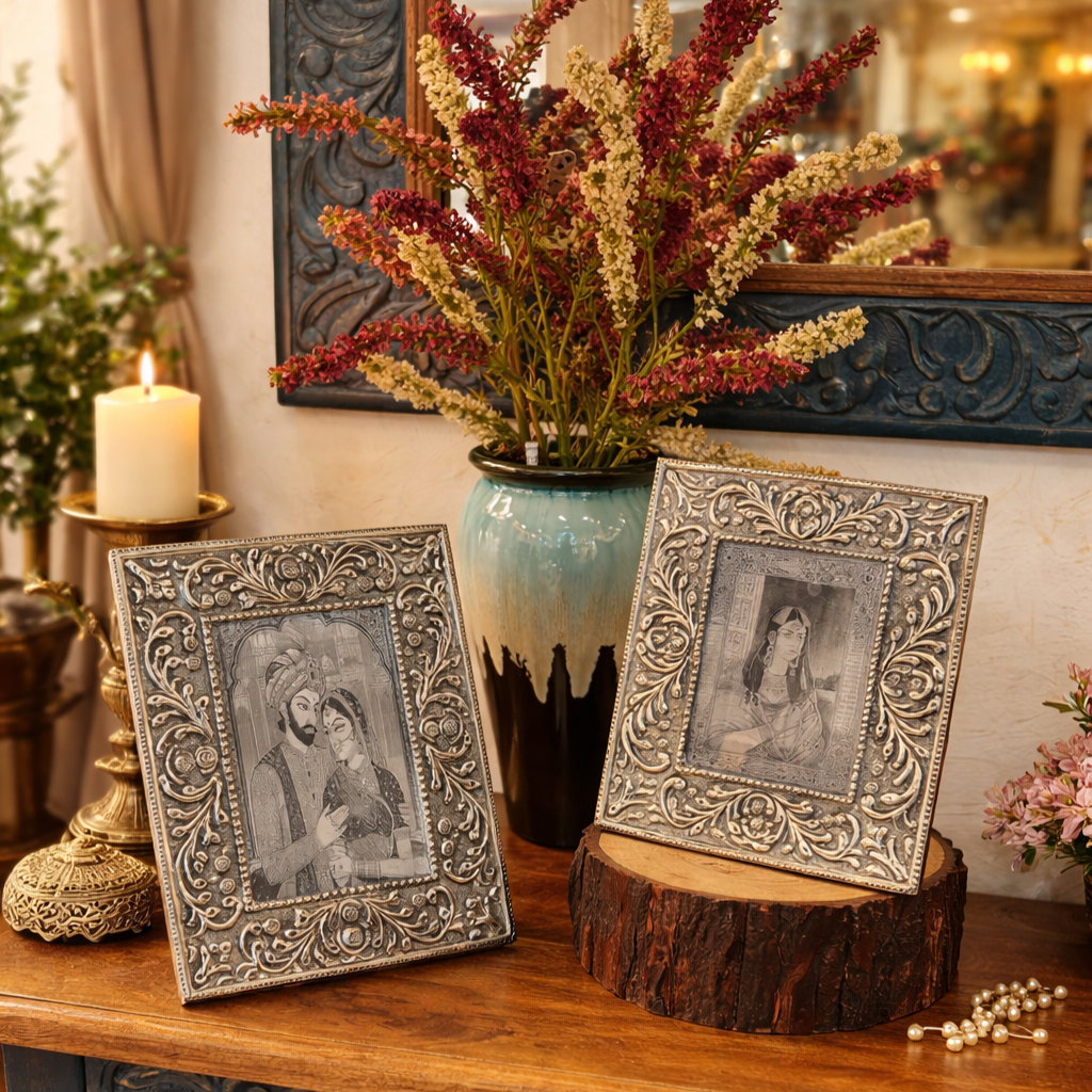 Luxury antique silver handcrafted photo frames with intricate floral embossing, styled on a wooden console with floral décor and warm ambient lighting in a royal heritage home setting.