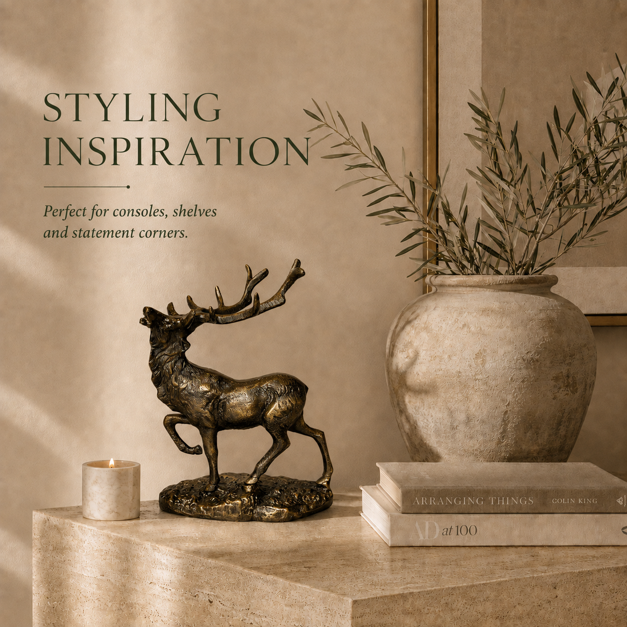 Royal Stag antique brass deer sculpture styled on a luxury console table with books, candle, and ceramic vase in an elegant modern living room.