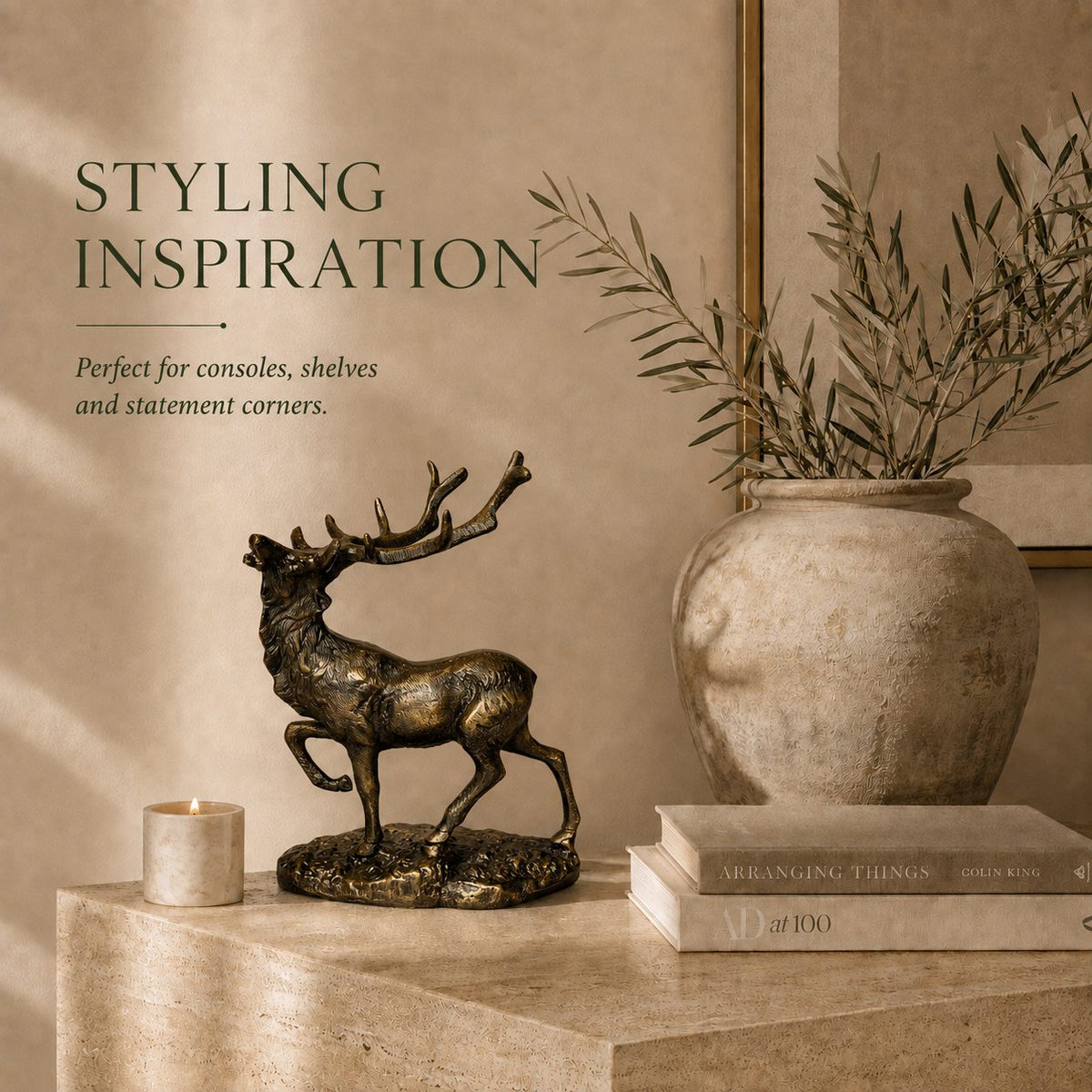 Royal Stag antique brass deer sculpture styled on a luxury console table with books, candle, and ceramic vase in an elegant modern living room.