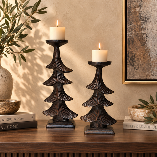 Rustic metal Christmas tree candle holder set styled with lit cream pillar candles on a luxury wooden console table.