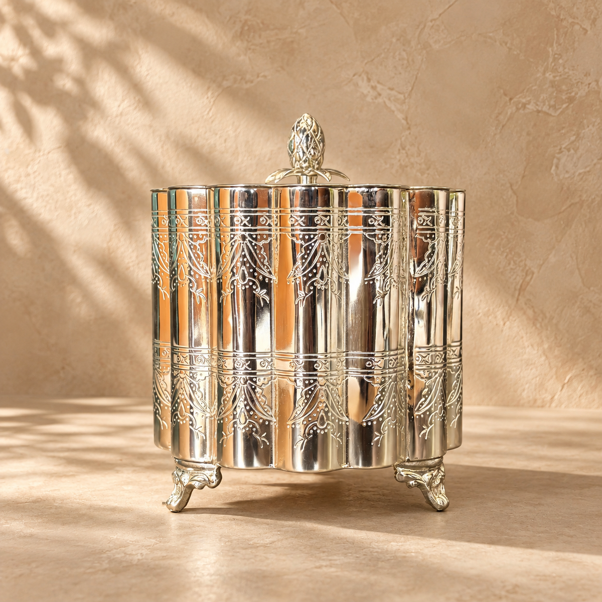 Silver Decorative Storage Container with Lid featuring an elegant engraved metal finish, decorative feet, and ornate finial, styled against a premium beige Venetian plaster backdrop, ideal for luxury home décor and tabletop styling.