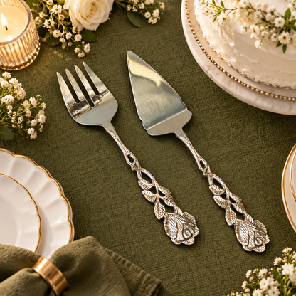 Luxury silver rose handle cake server and matching pastry fork set styled on a dark olive green table mat with elegant dinnerware and floral accents, ideal for weddings, celebrations and cake serving.