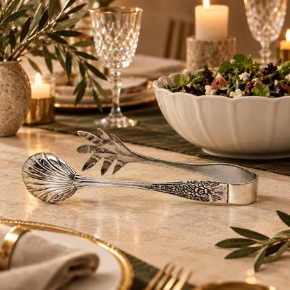 Luxury silver salad serving tongs displayed on an elegant dining table beside a fresh salad bowl, handcrafted stainless steel serving accessory by Inara Home Decor.