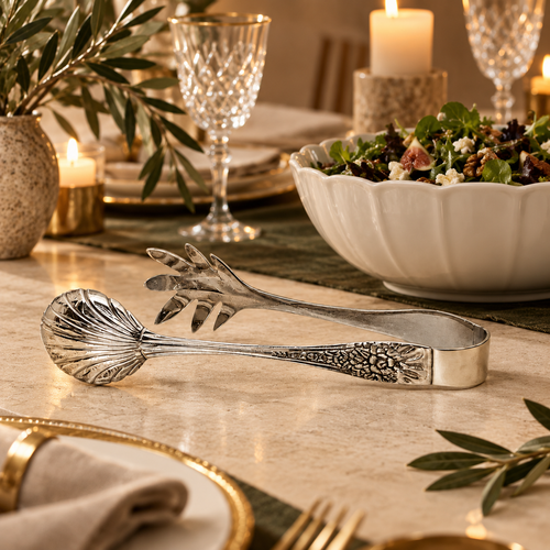 Luxury silver salad serving tongs displayed on an elegant dining table beside a fresh salad bowl, handcrafted stainless steel serving accessory by Inara Home Decor.