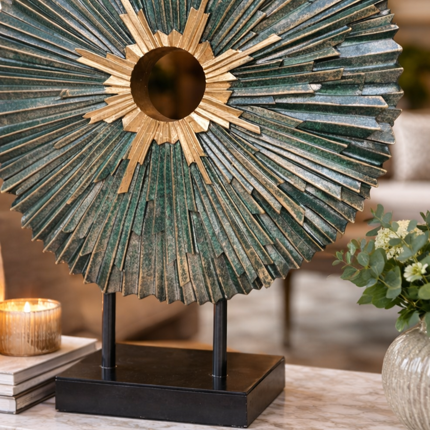 Close-up detail of a green and gold sunburst metal sculpture highlighting layered texture, styled as a luxury home decor accent on a console table