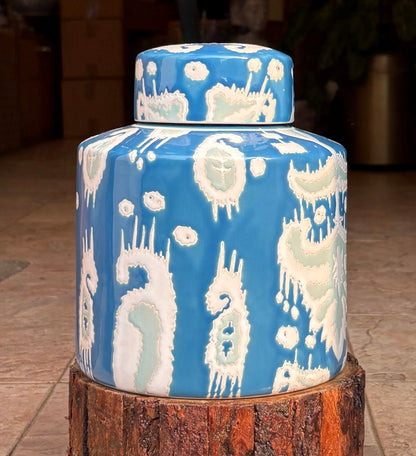 A tall, tapered ceramic vase with a narrow neck, featuring an intricate teal and white ikat motif on a deep blue glazed background, perfect for luxury interior styling.