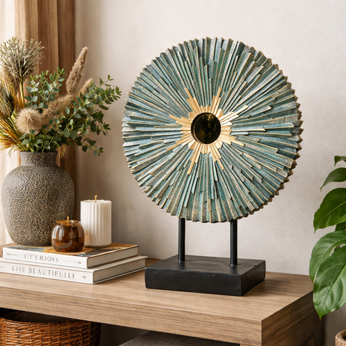 Teal and gold sunburst tabletop sculpture with central mirror, styled on a wooden console with decorative vase, candles, and books for elegant home décor.